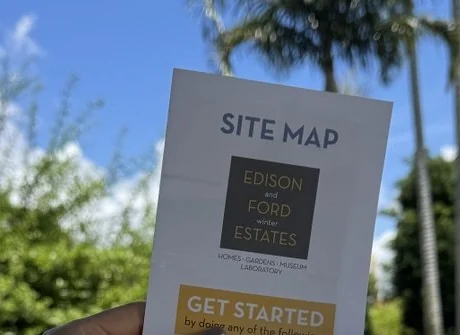 Garden site map held against palms and bright Florida sky